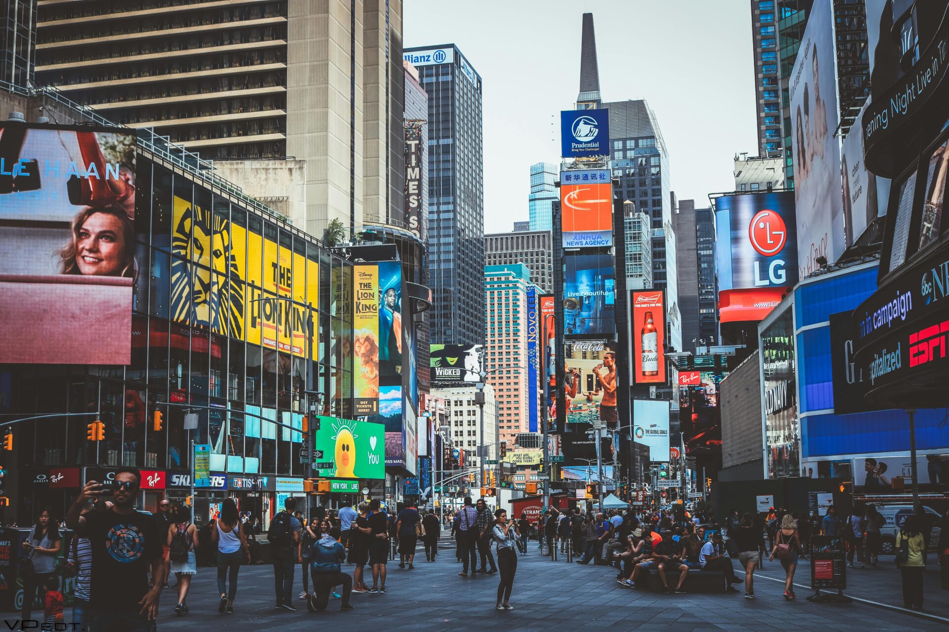 Bustling daytime view of Times Square with crowds, skyscrapers, and iconic billboards in New York City.