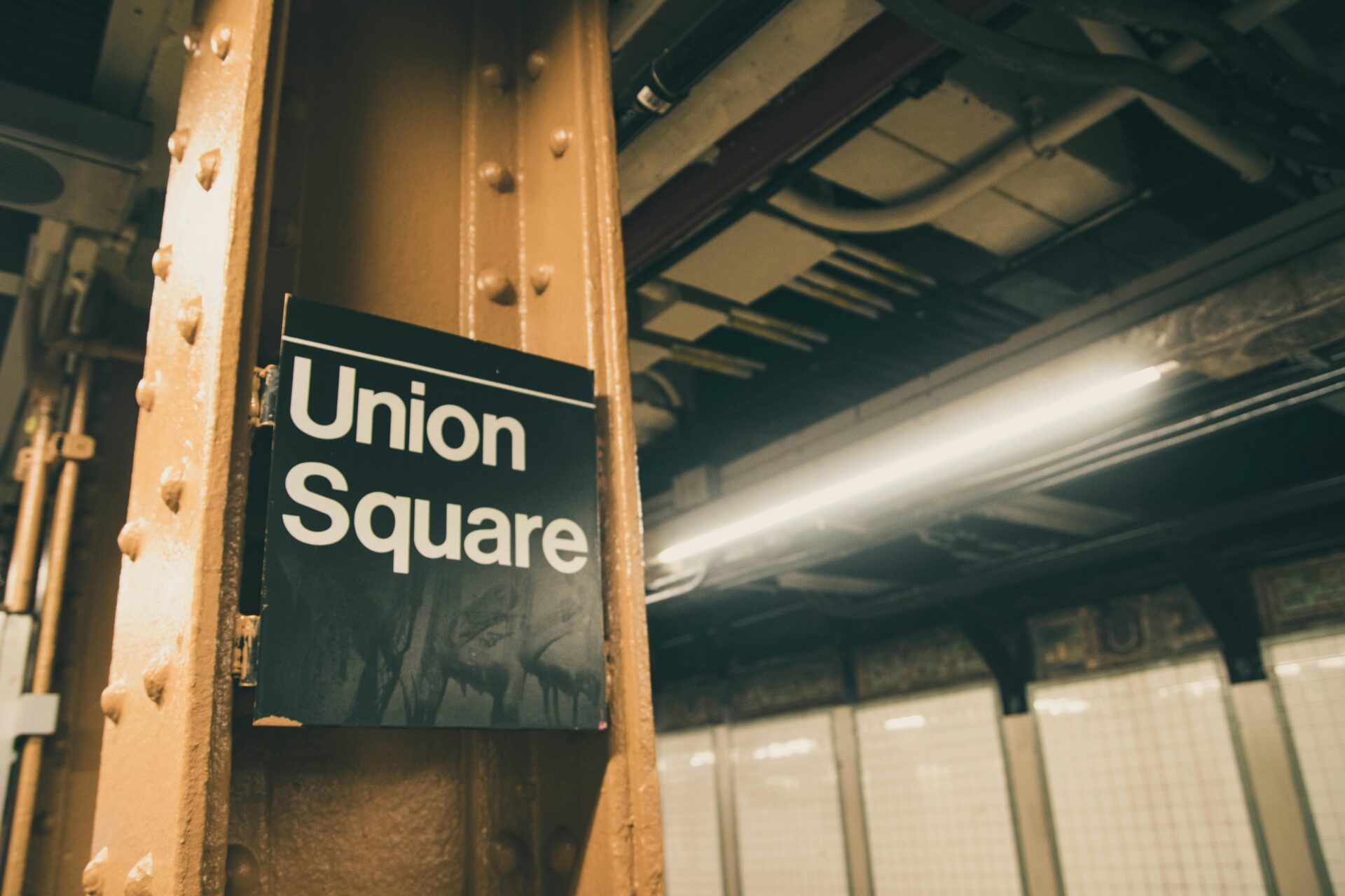 Close-up of Union Square subway signage with industrial metal support beams.