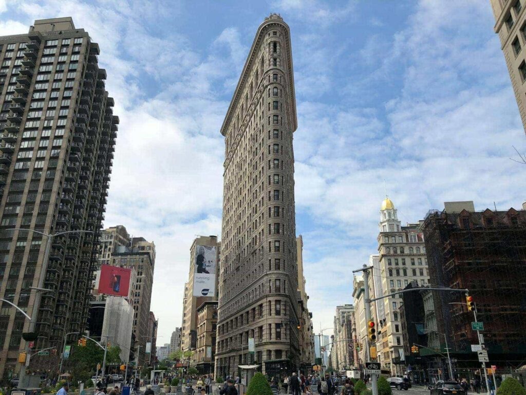 Iconic view of the Flatiron Building surrounded by city life in New York City.