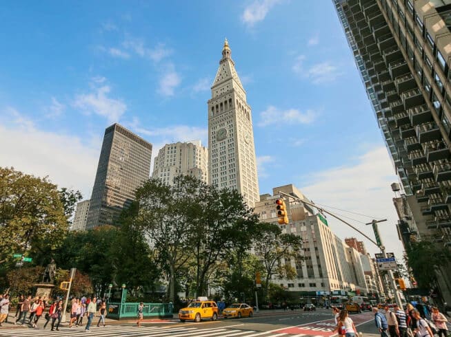 A lively street scene in Manhattan's Flatiron District with iconic architecture and busy pedestrians.