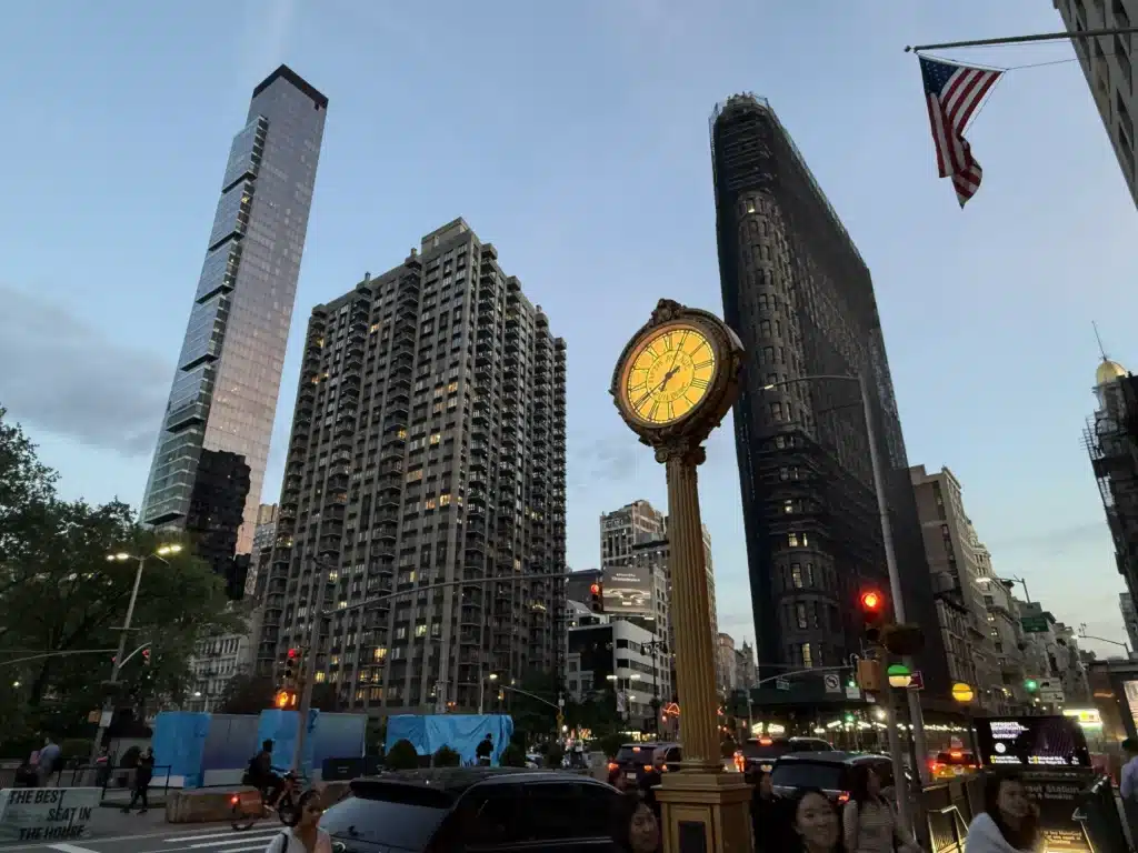 The Flatiron Building and the Fifth Avenue Building street clock at dusk.